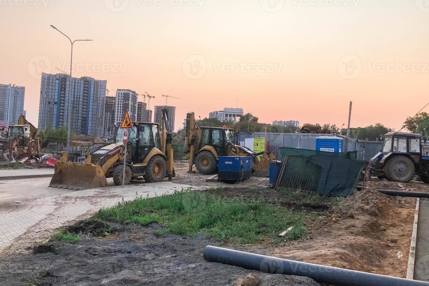 local de construção. equipamentos de construção em cores brilhantes fica no local ao lado do canteiro de obras. escavadoras, gruas de construção para a construção de casas foto