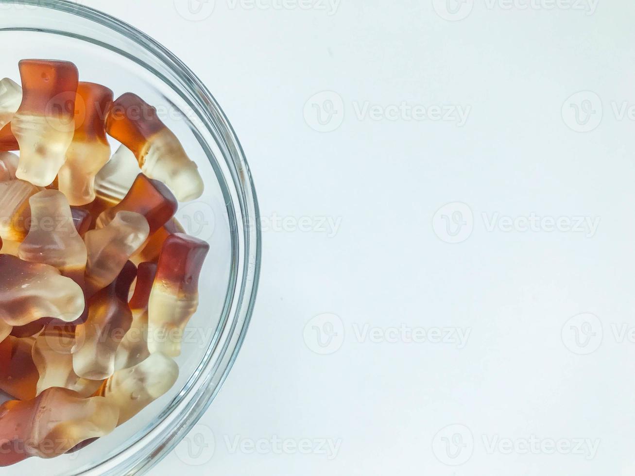 a marmelada em forma de garrafa está em um prato pequeno, redondo e transparente. doces gelatinosos de dar água na boca. fotografia macro, um ângulo incomum. doces e guloseimas infantis foto