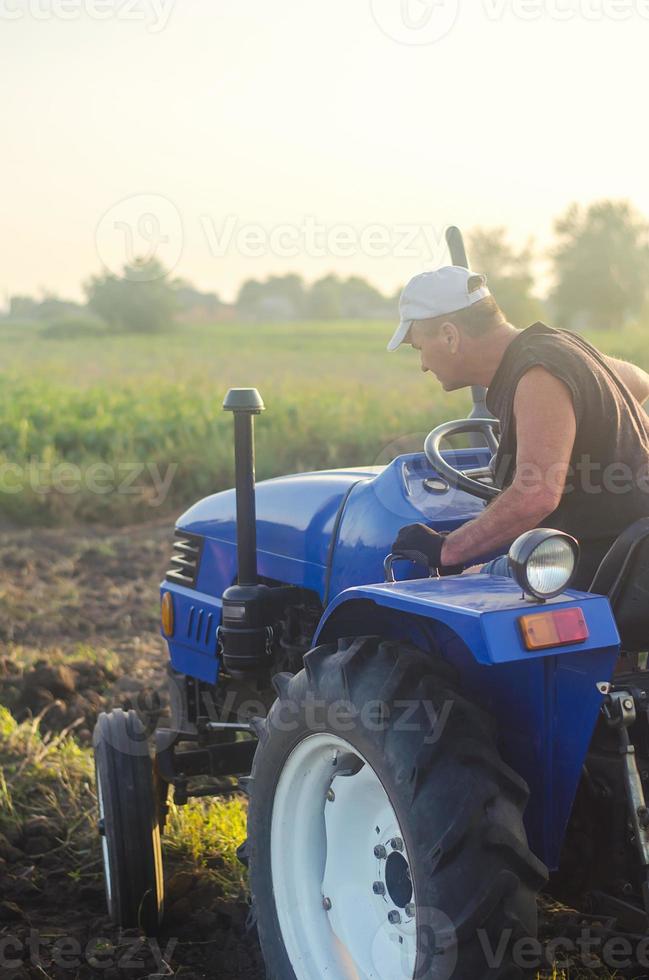 um agricultor em um trator atravessa o campo agrícola. campanha de colheita de batata. agricultura, agricultura. colheita de batatas no outono. terras agrícolas do campo. agricultura foto