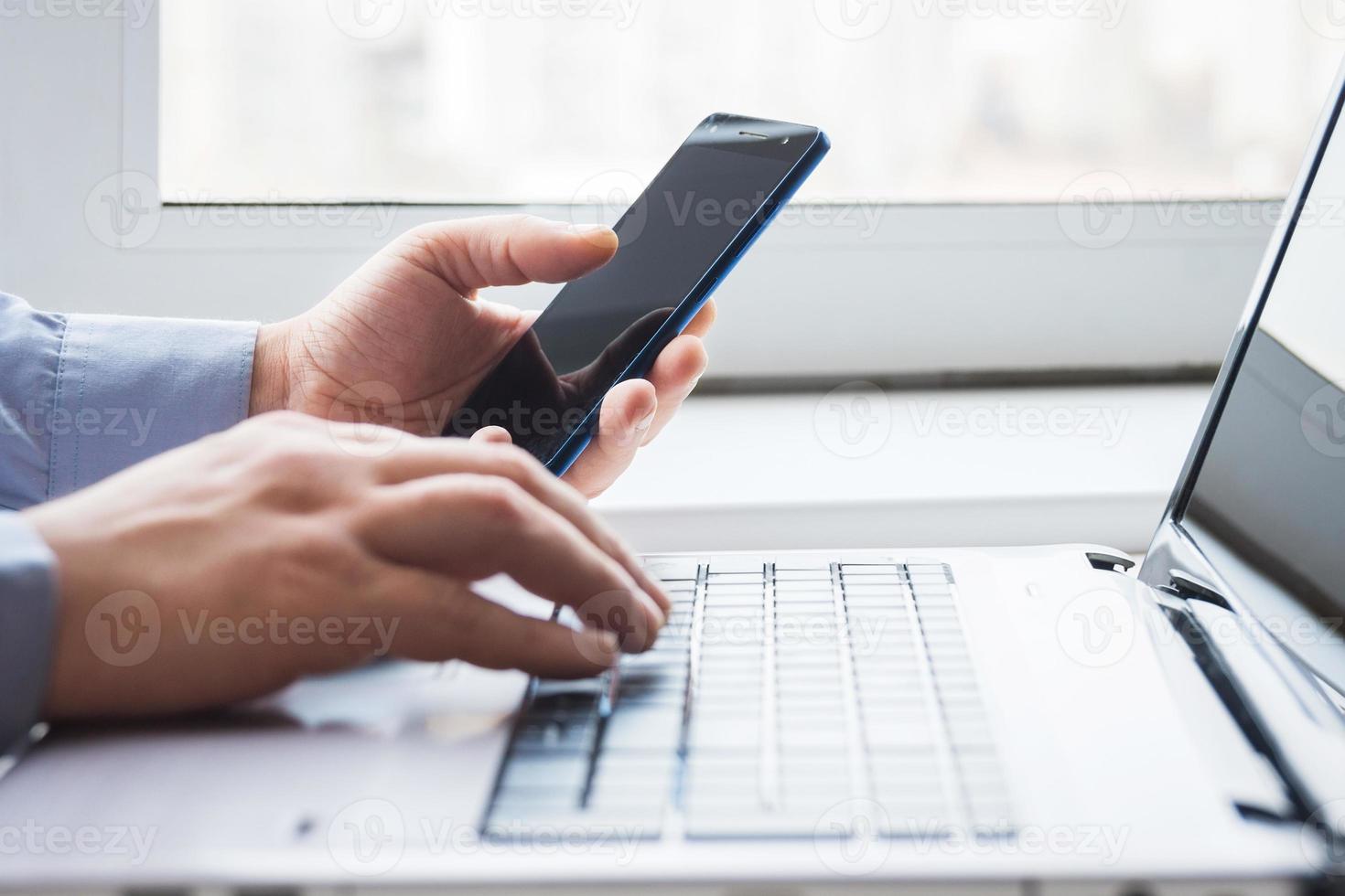 homem atrás de laptop com smartphone foto