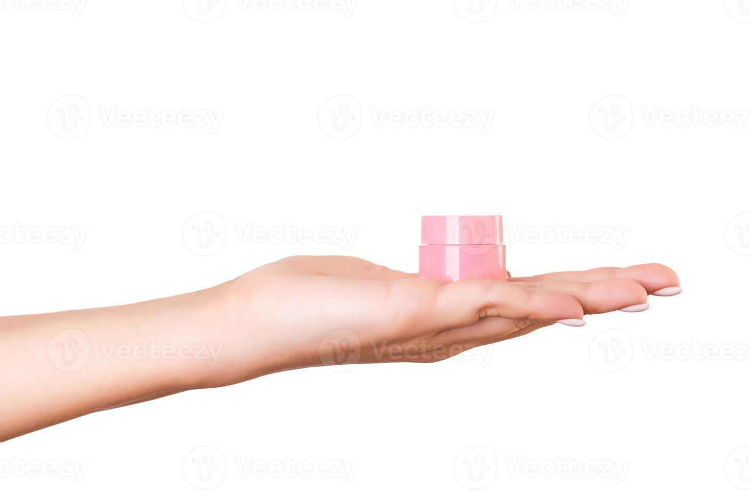 mão feminina segurando o frasco de creme de loção isolado. garota dá produtos cosméticos de jarra em fundo branco foto