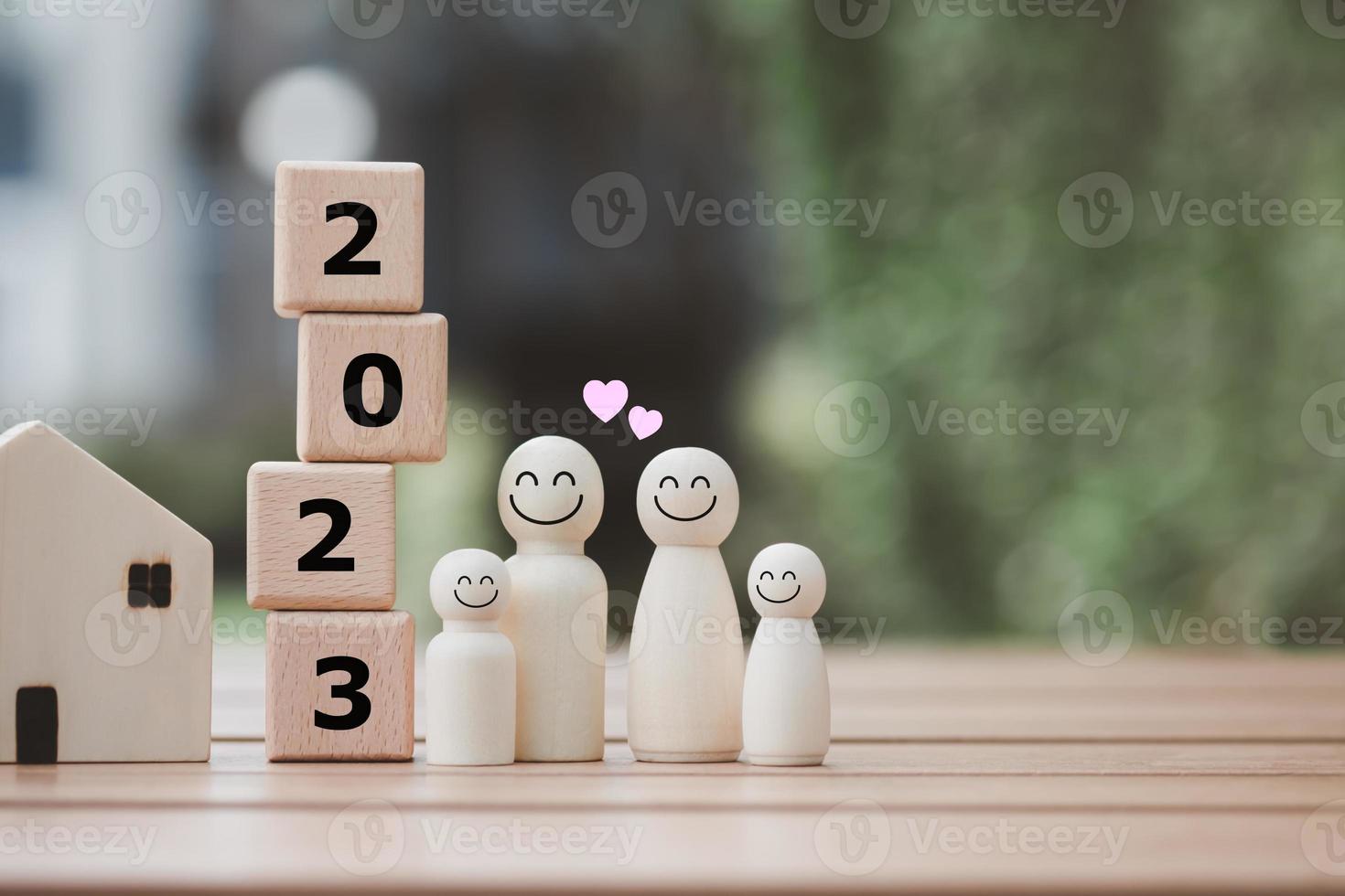 2023 feliz ano novo. família feliz, planejamento orçamentário, seguro, casa e imóveis, planejar e economizar dinheiro para o futuro. família de figuras humanas com rosto sorridente e coração com blocos de madeira número 2023. foto