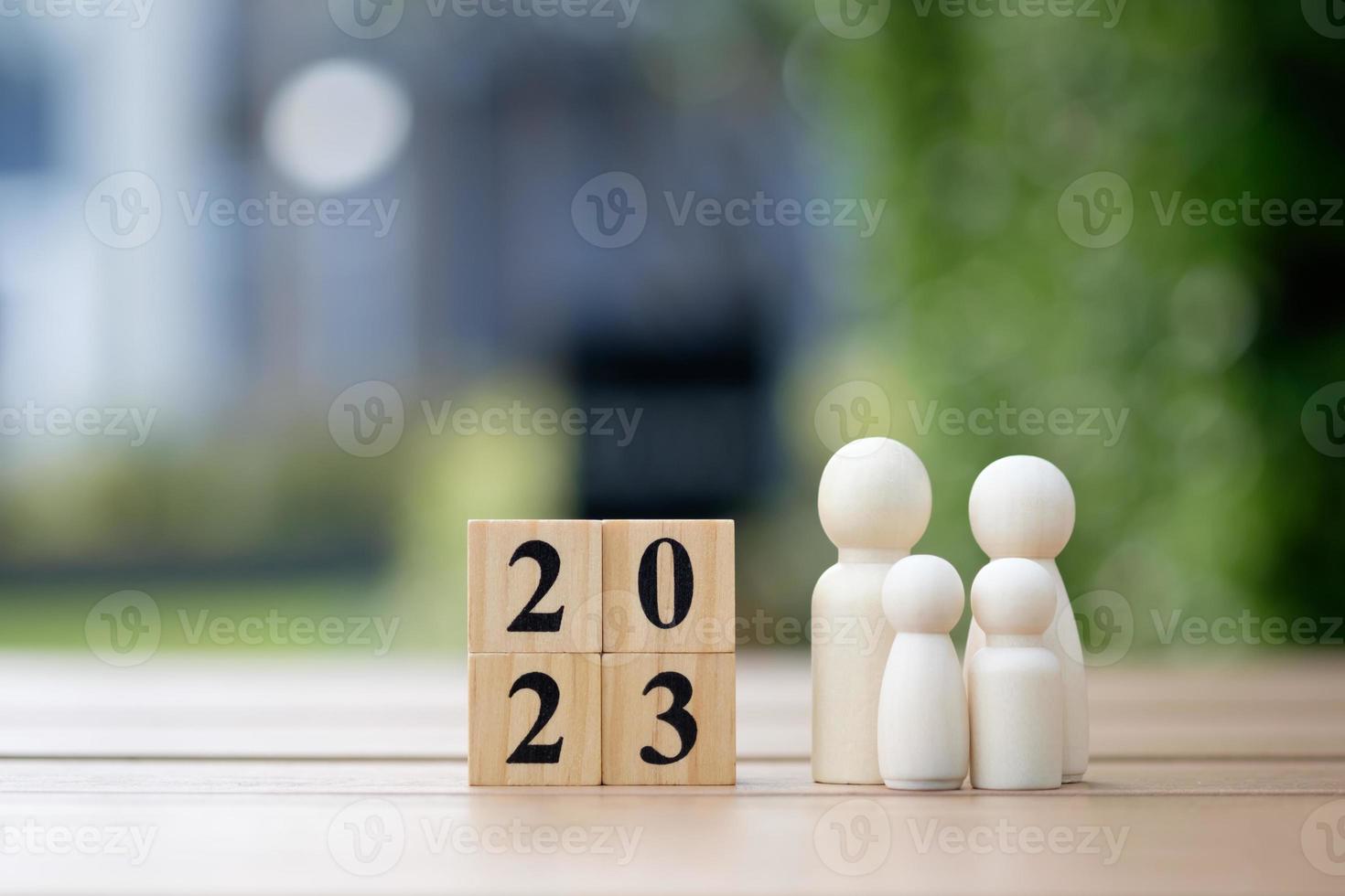 2023 feliz ano novo. família feliz, planejamento orçamentário, seguro, plano e economizando dinheiro para o futuro. família de figuras humanas com rosto sorridente e coração com blocos de madeira número 2023. foto