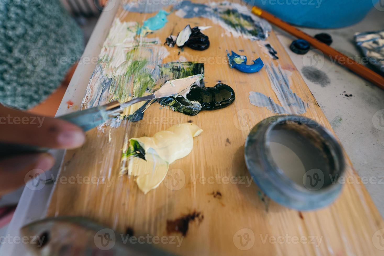 close-up de tintas de mistura de mão de mulher na paleta foto
