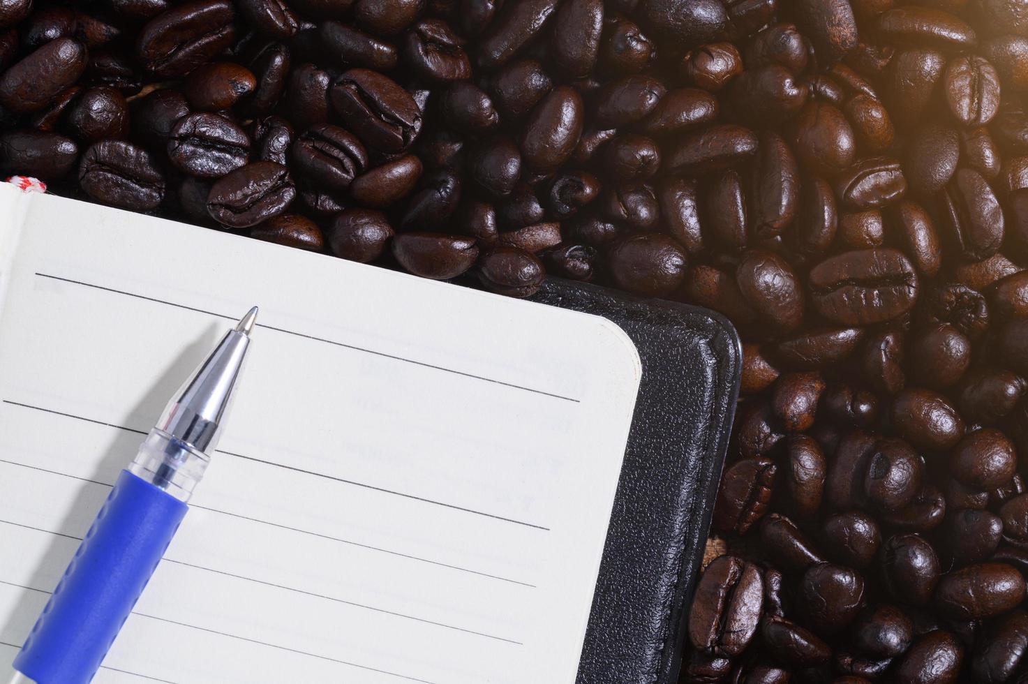 caderno e caneta em grãos de café foto