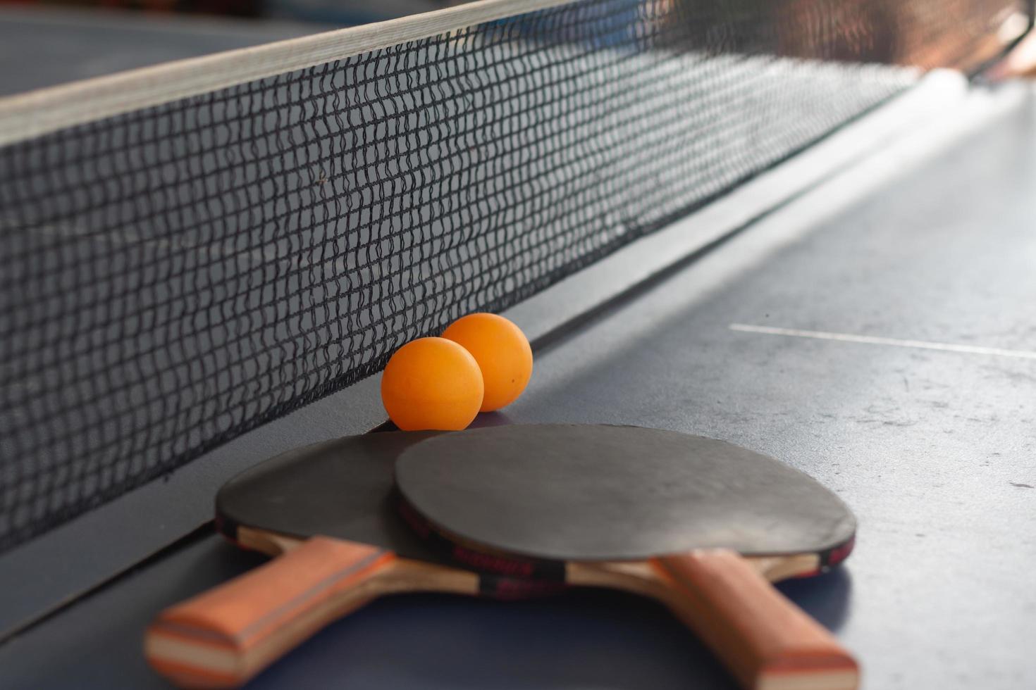 feche bolas laranja com raquetes de tênis de mesa foto