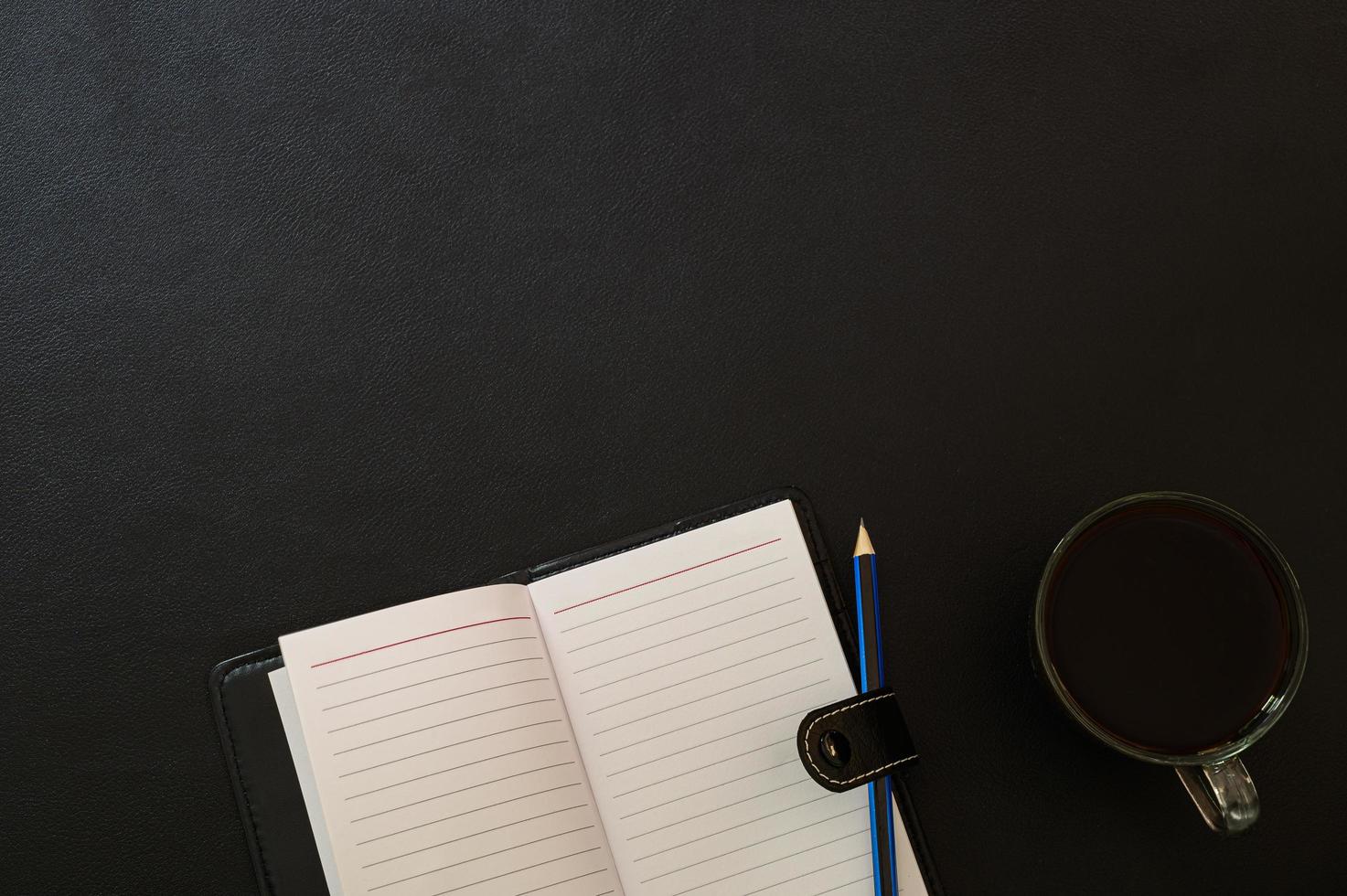 caderno, lápis e uma caneca de café na mesa, vista de cima foto