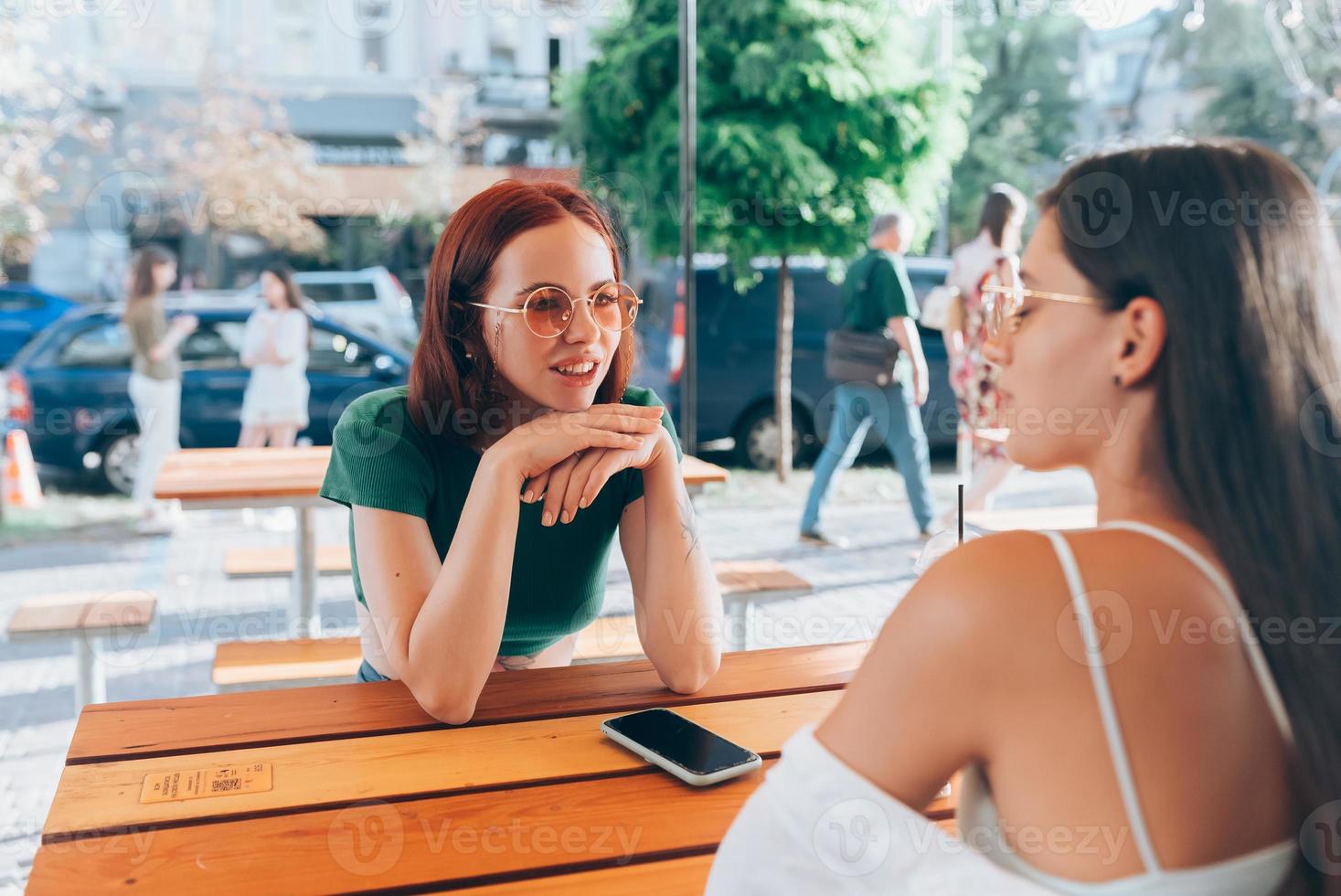 duas namoradas bonitas conversando enquanto está sentado em um bar ao ar livre foto