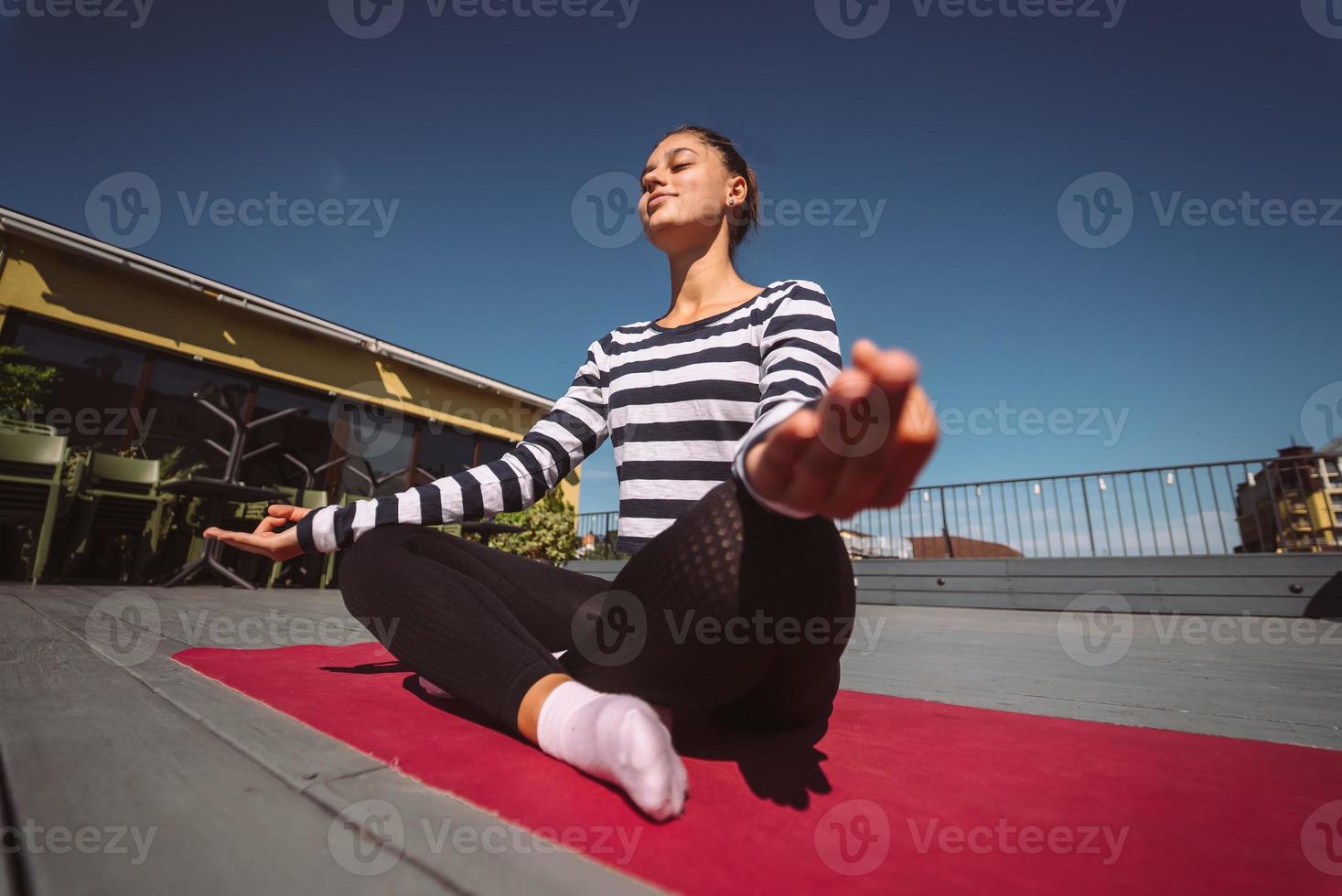 jovem meditando em pose de lótus no telhado do edifício foto