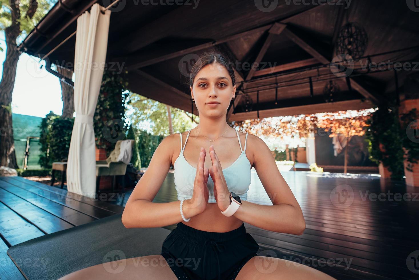 jovem sentada em posição de lótus com as mãos em namastê. foto