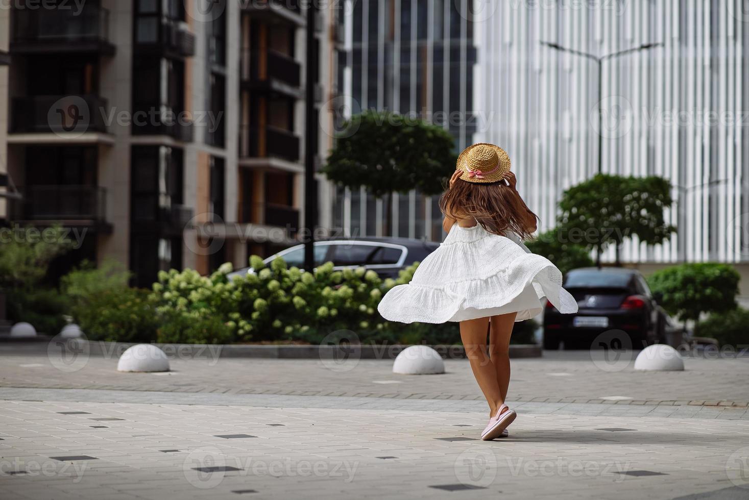 linda mulher bonita de vestido branco andando na rua da cidade foto