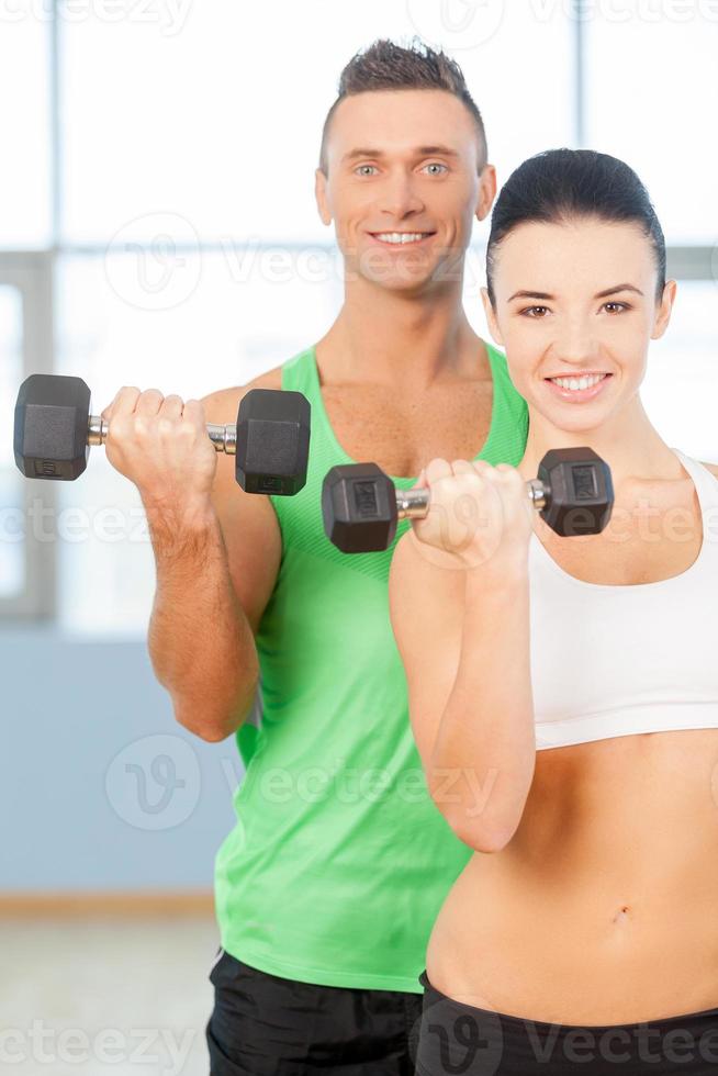 treino com halteres. casal levantando halteres em uma academia e sorrindo foto