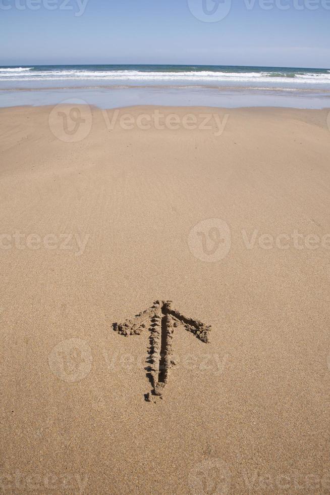 seta escrita na areia da praia foto