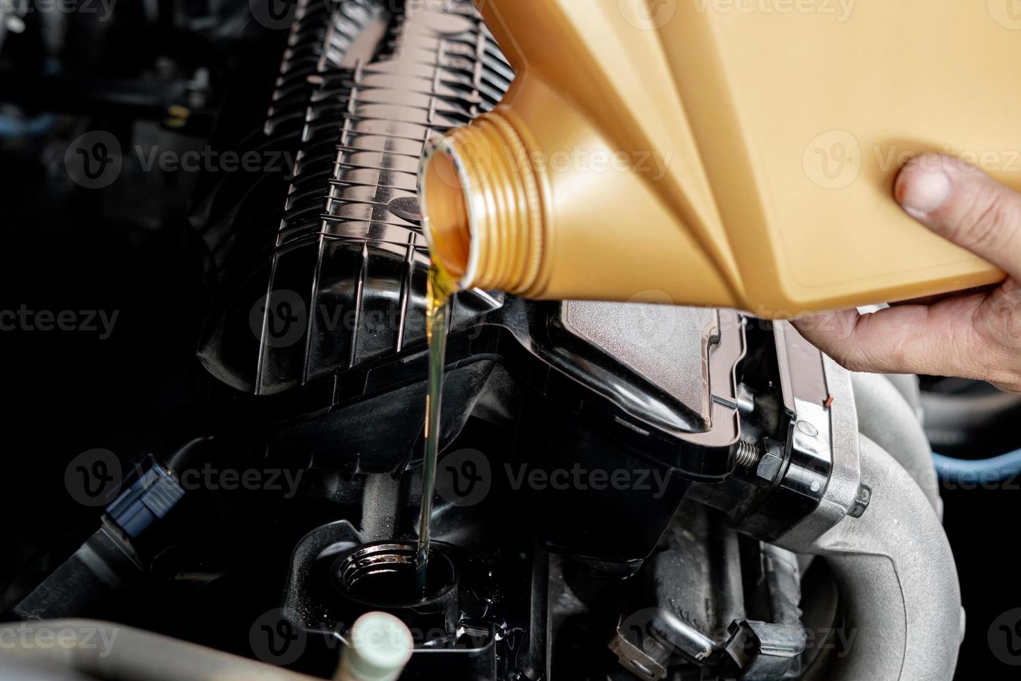 um homem derramando óleo no motor do carro. óleo fresco derramado durante uma mudança de óleo para um carro adicionando óleo de motor na manutenção do motor do motor, combustível de energia do carro e conceito de serviço foto