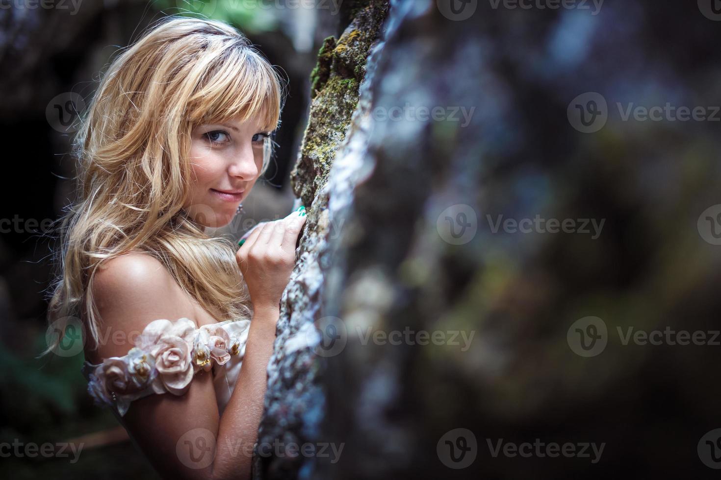 linda loira em um vestido branco com um espartilho em uma caverna escura profunda foto