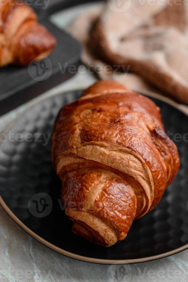 delicioso croissant crocante com chocolate com uma xícara de café revigorante em um fundo claro de concreto foto