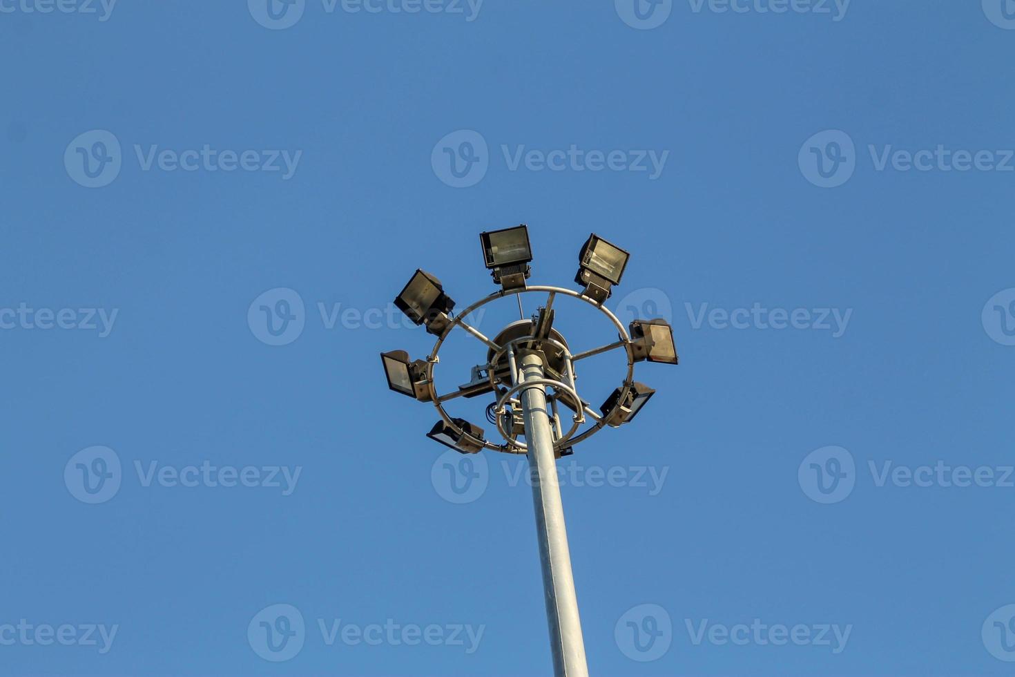 um grande poste elétrico cheio de holofotes no céu azul foto