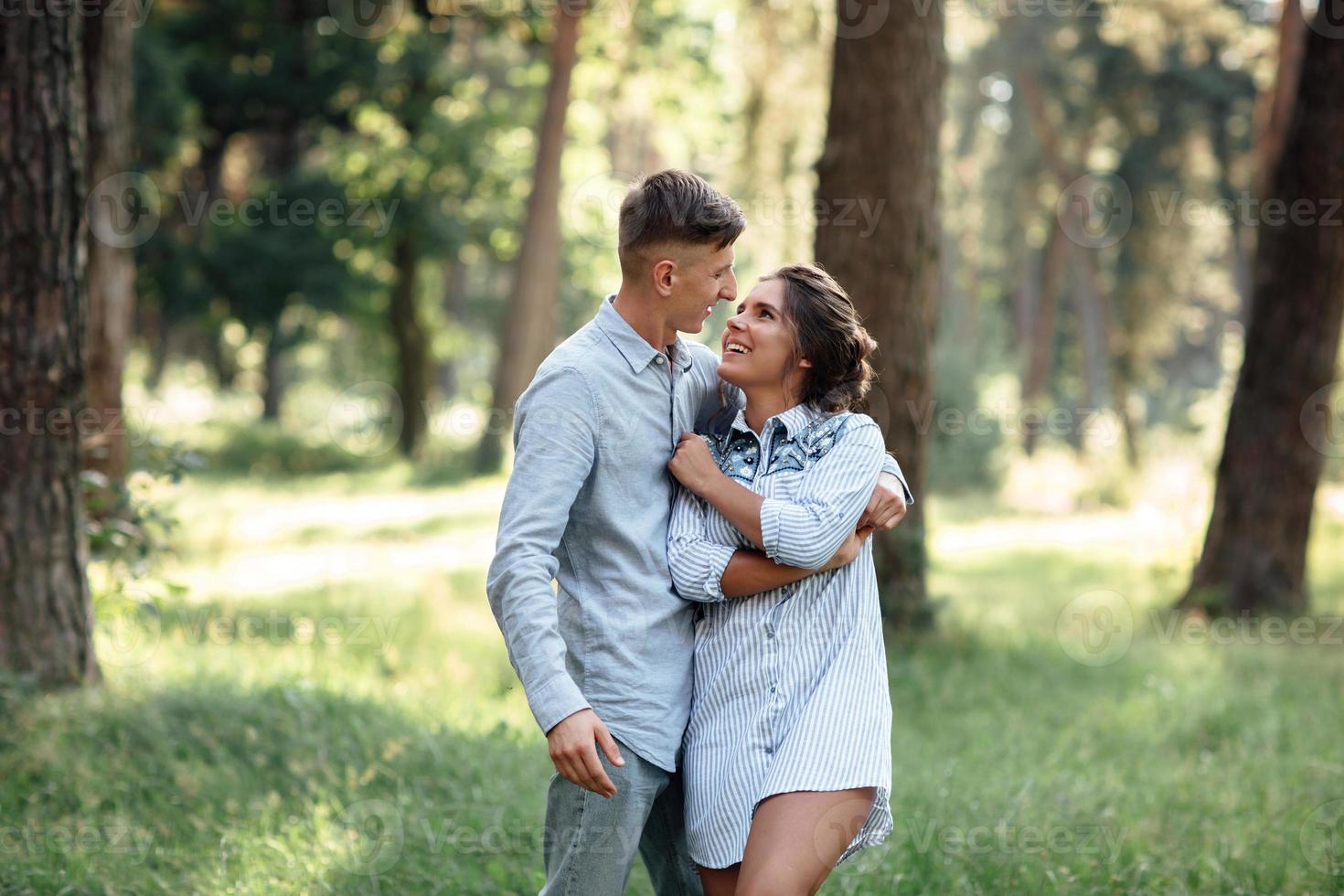 homem e mulher jovem alegre estão abraçando ao ar livre no parque de verão. namoro e férias românticas. casal apaixonado gentilmente olhando um ao outro em dia ensolarado. amor e relacionamentos entre os jovens foto