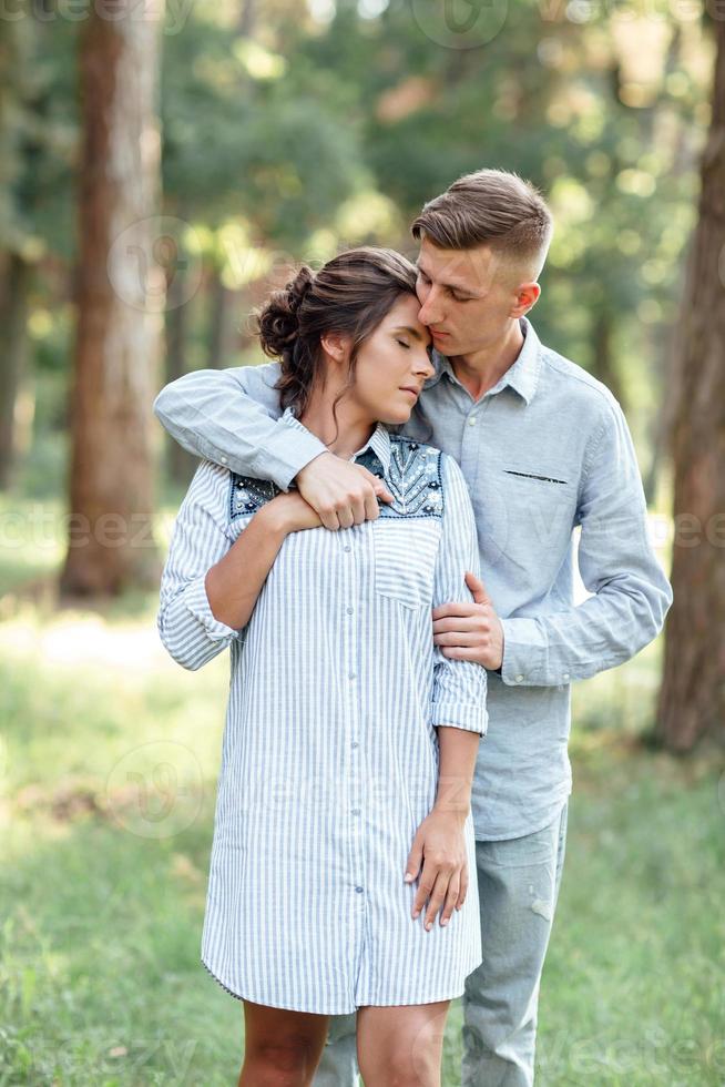 homem e mulher jovem alegre estão abraçando ao ar livre no parque de verão. namoro e férias românticas. casal apaixonado gentilmente olhando um ao outro em dia ensolarado. amor e relacionamentos entre os jovens foto