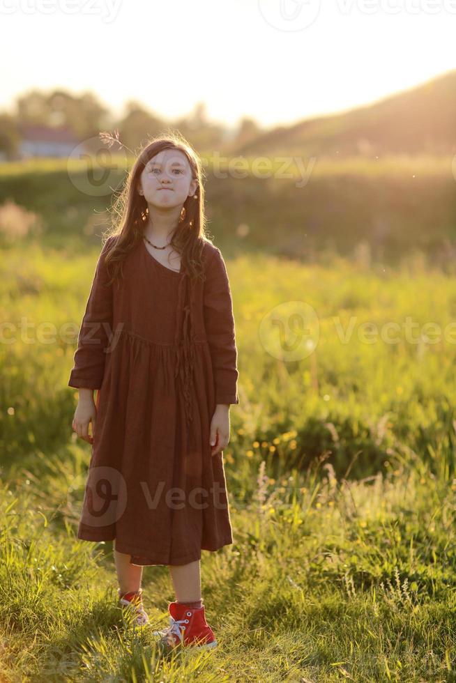 linda menina bonitinha brincando ao ar livre ao pôr do sol, andando e se divertindo, infância feliz. férias ensolaradas de verão foto