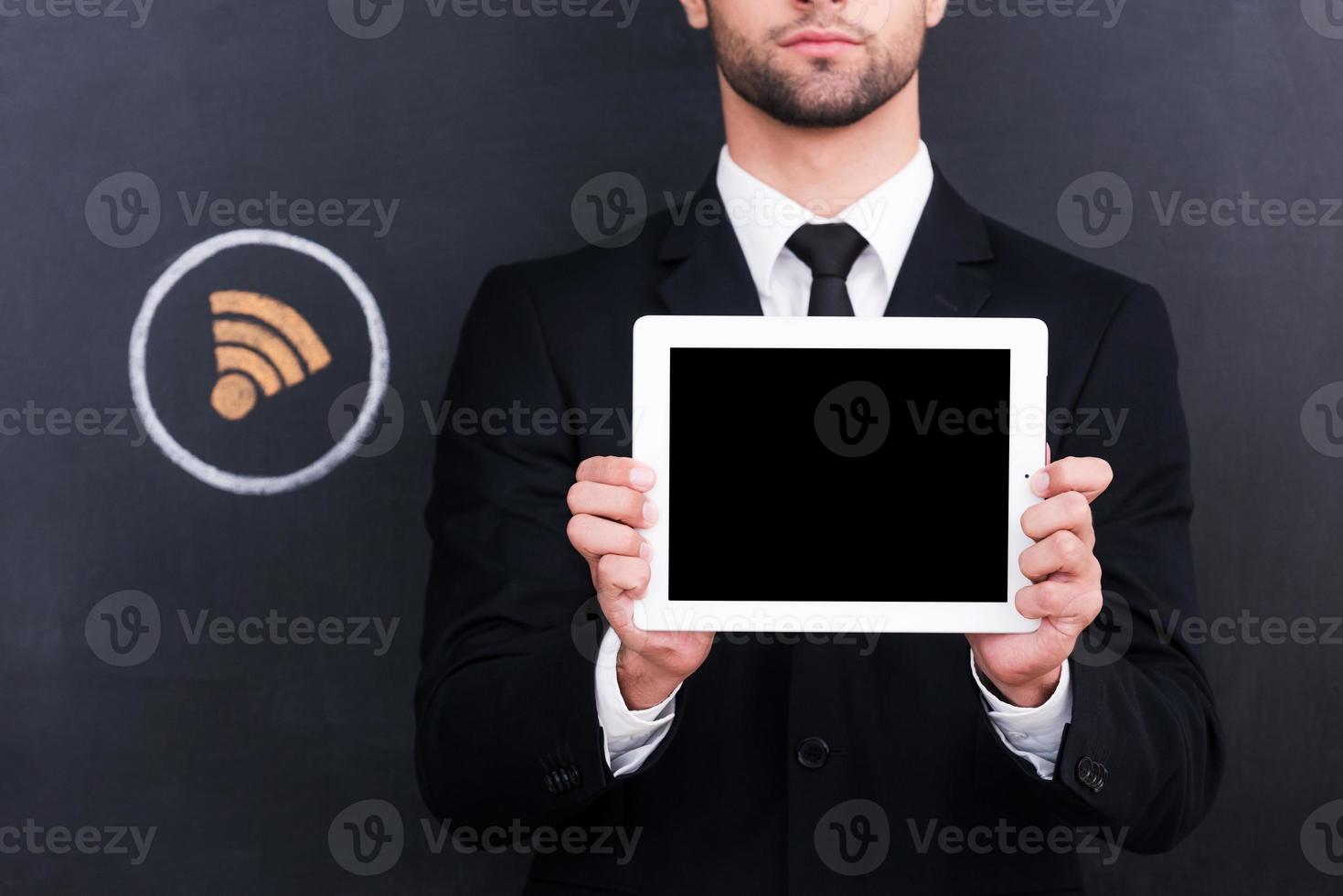 close-up wi-fi gratuito de jovem bonito segurando tablet digital em pé contra o compartilhamento de símbolo de giz desenho no quadro-negro foto