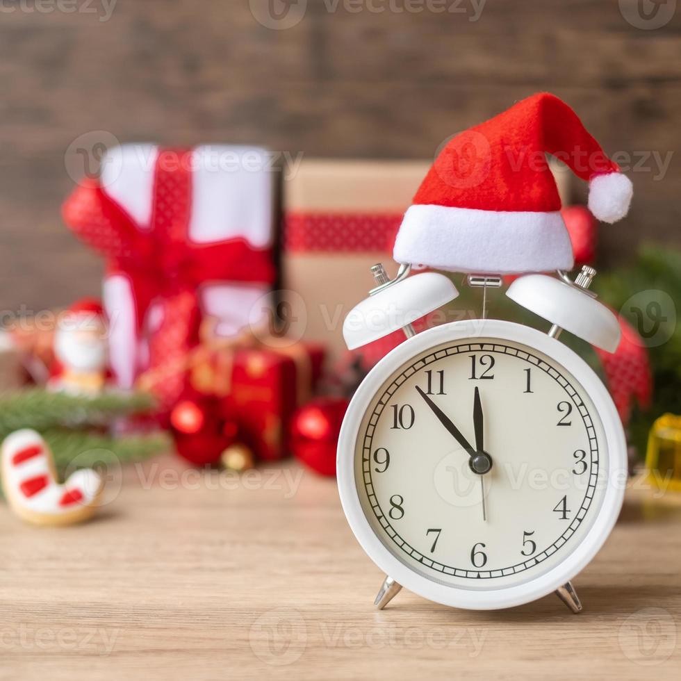 feliz natal com despertador vintage e decoração de natal na mesa de madeira. conceito de festa, feriado e dia de boxe foto