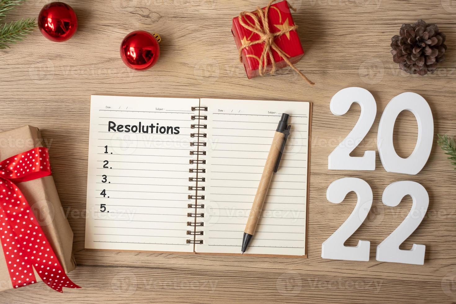 Resoluções de 2022 com notebook, presente de natal e caneta na mesa de madeira. natal, feliz ano novo, objetivos, lista de tarefas, início, estratégia e conceito de plano foto