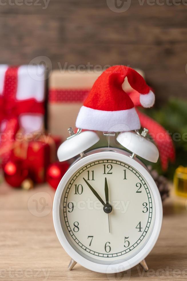 feliz natal com despertador vintage e decoração de natal na mesa de madeira. conceito de festa, feriado e dia de boxe foto