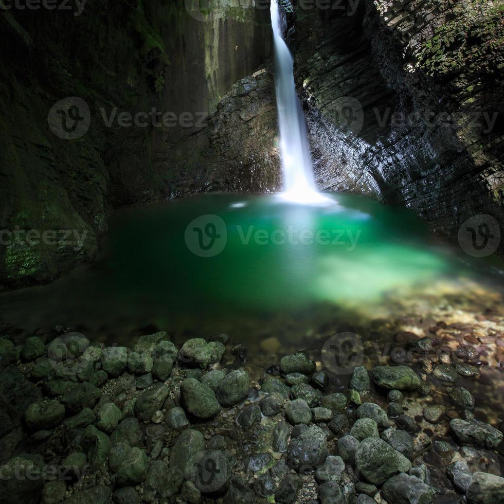 cachoeira romântica fluindo por uma fenda para o lago verde foto
