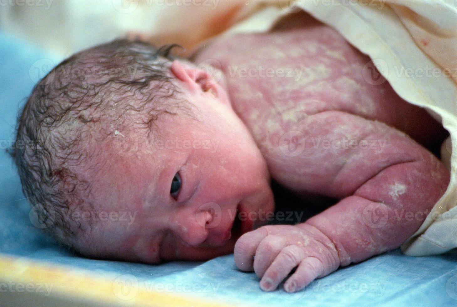 menina recém-nascida enrolada em uma toalha esperando para ser limpa foto