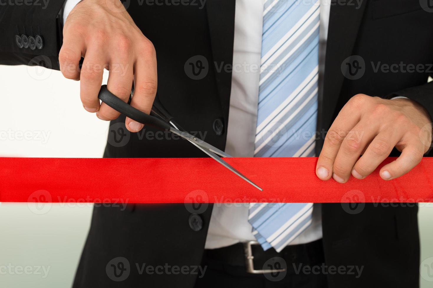 empresário cortando fita vermelha com tesoura foto