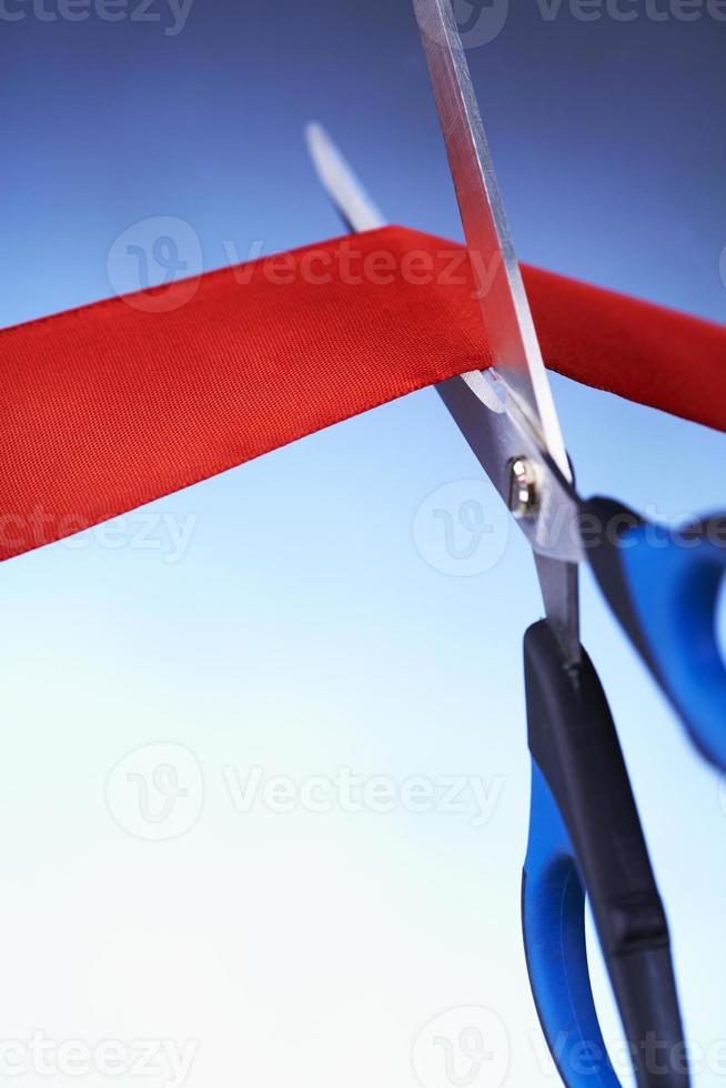 imagem aproximada de uma tesoura cortando uma fita vermelha foto