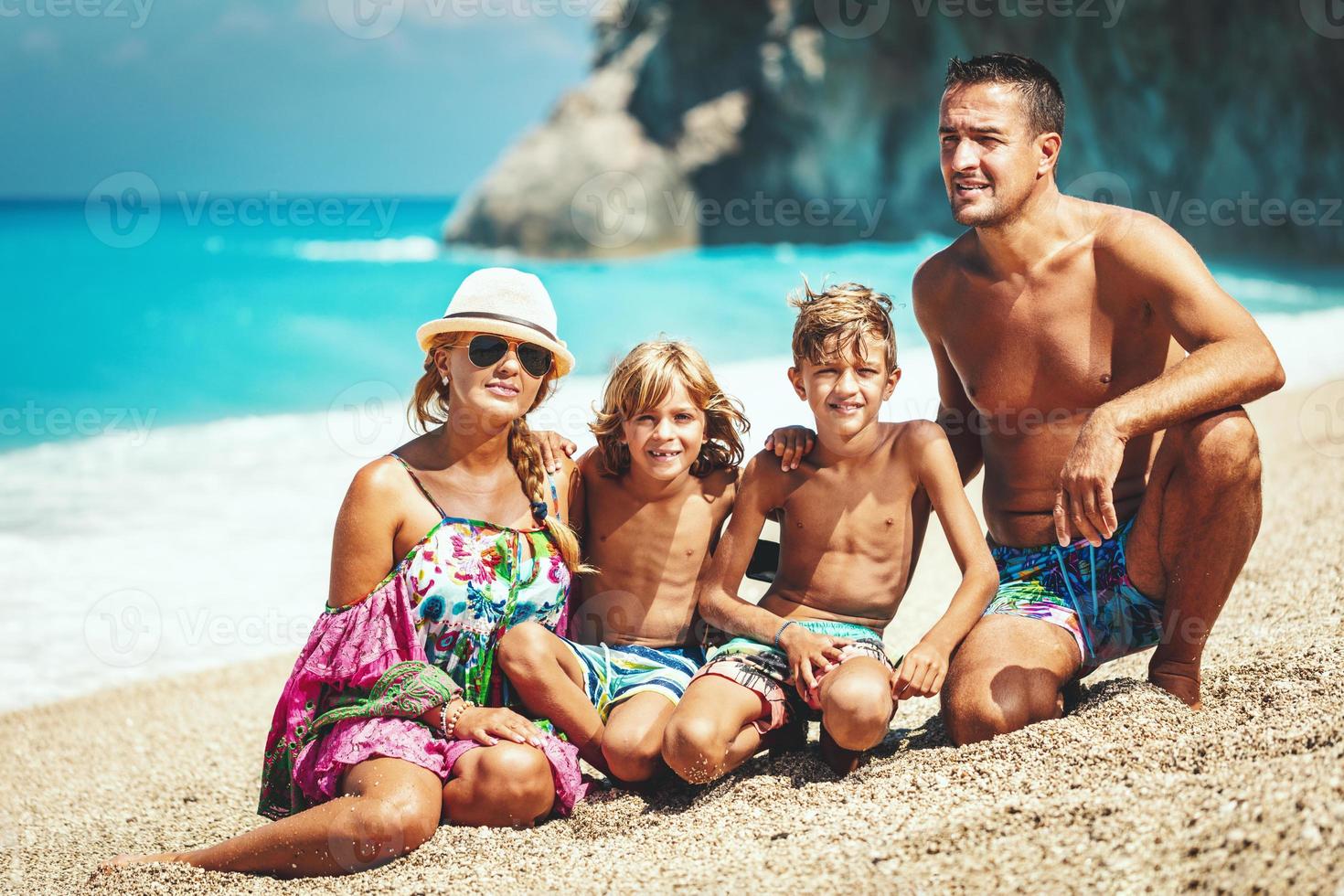 feliz família de quatro pessoas na praia foto