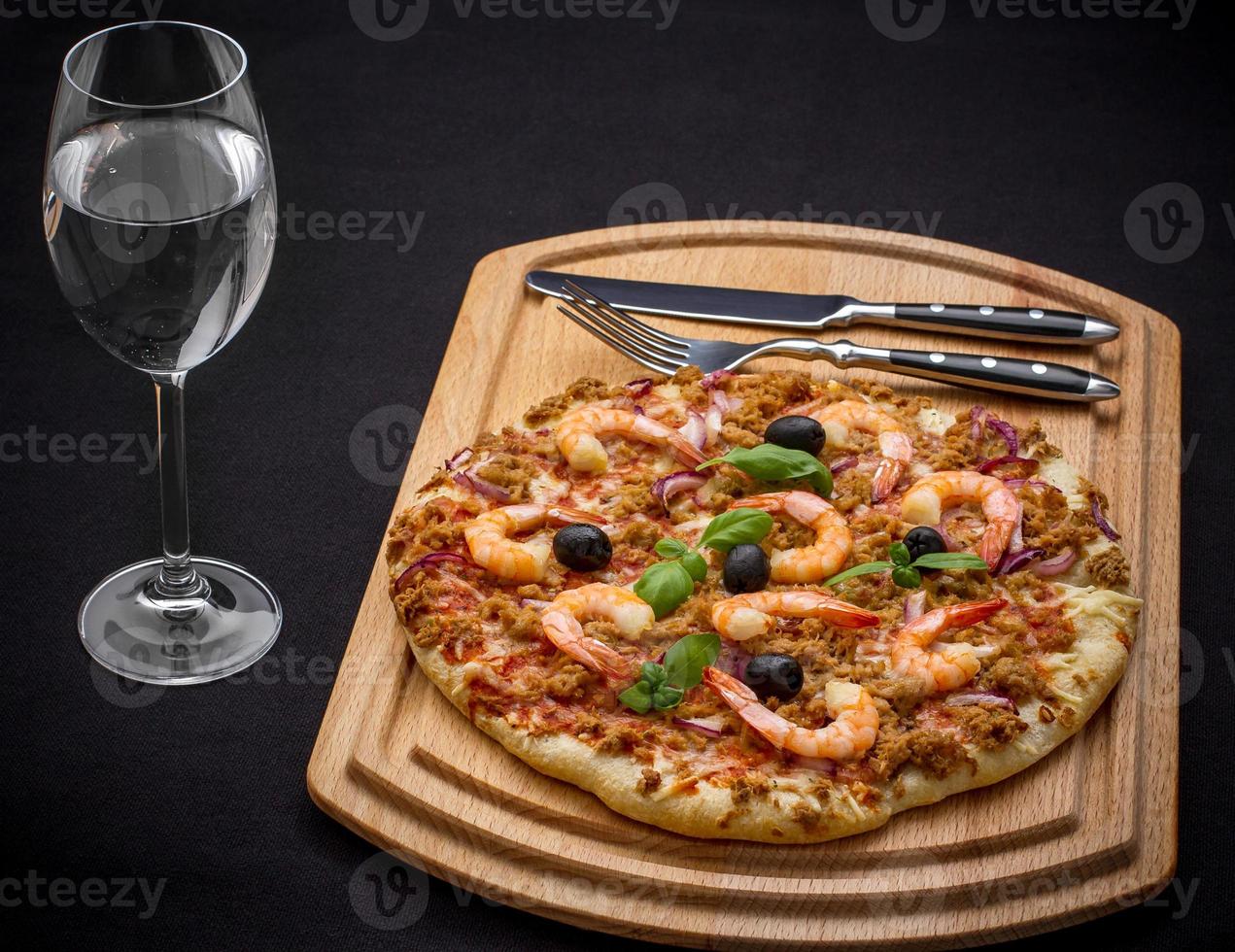 pizza de atum com camarão e água, talheres foto