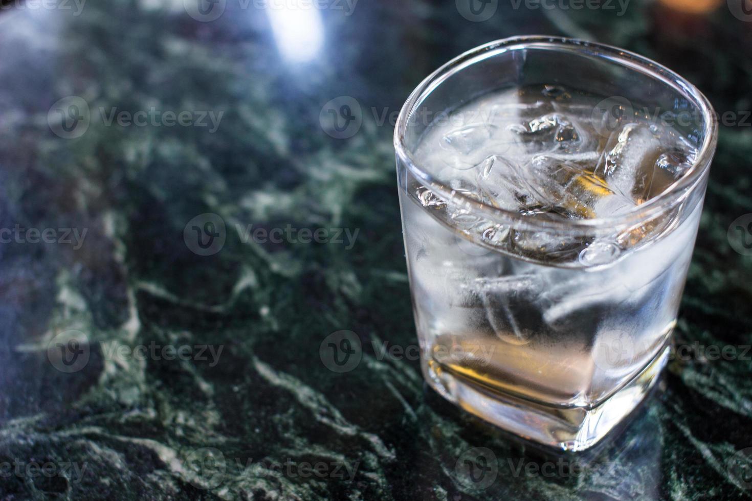 copo de água com um pouco de gelo na mesa foto