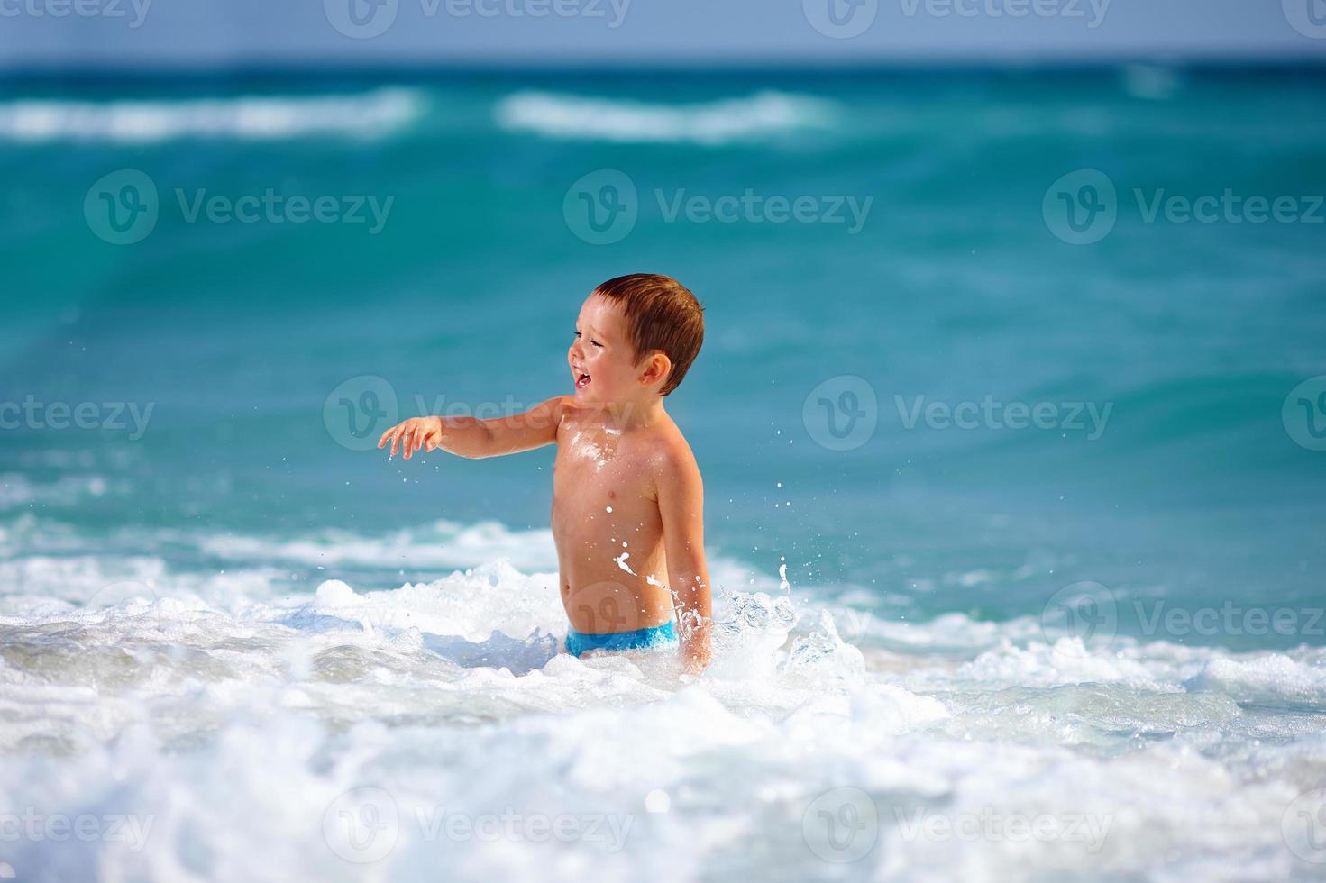garoto garoto feliz se divertindo na água do mar foto