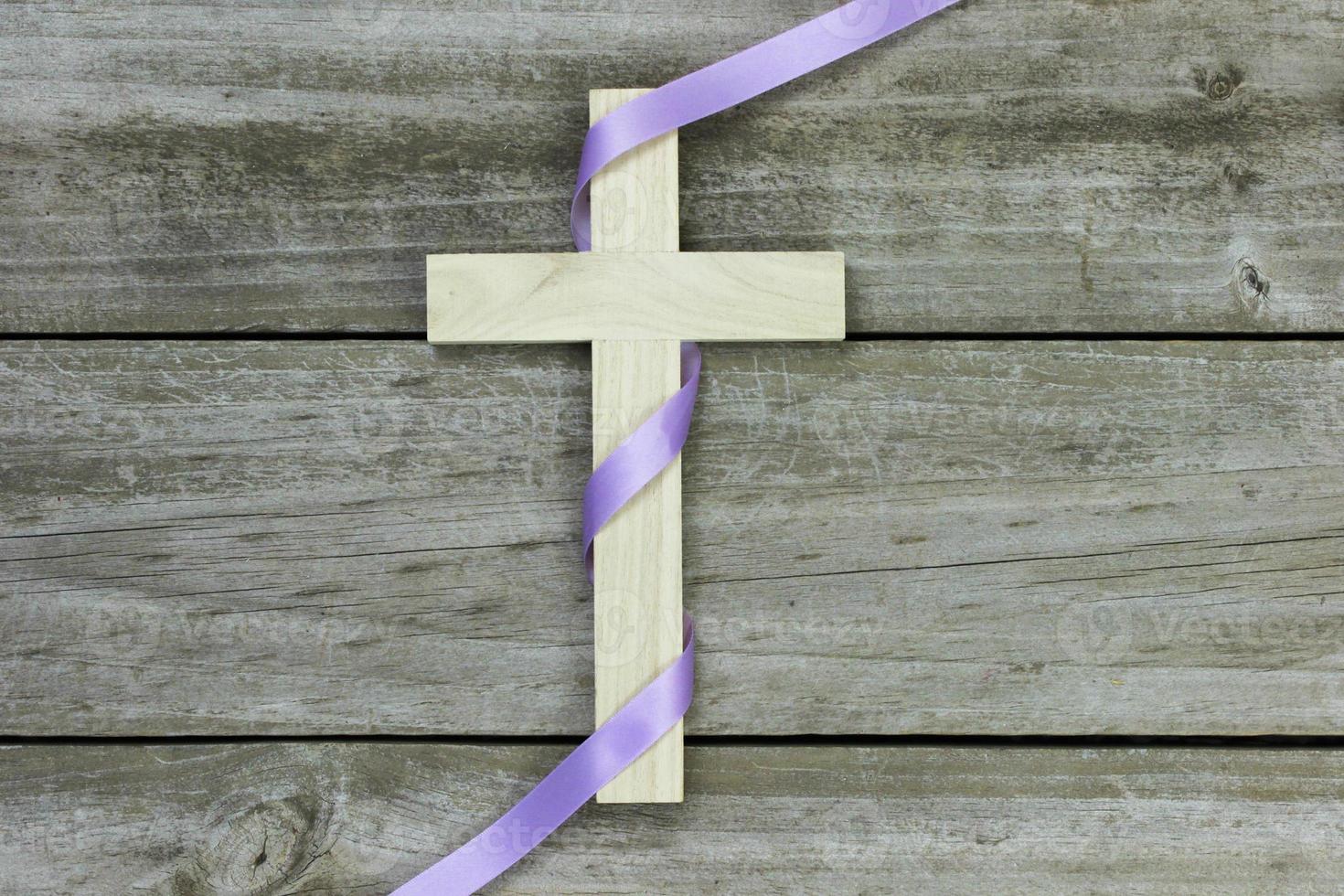 cruz de madeira com fita roxa em fundo de madeira foto
