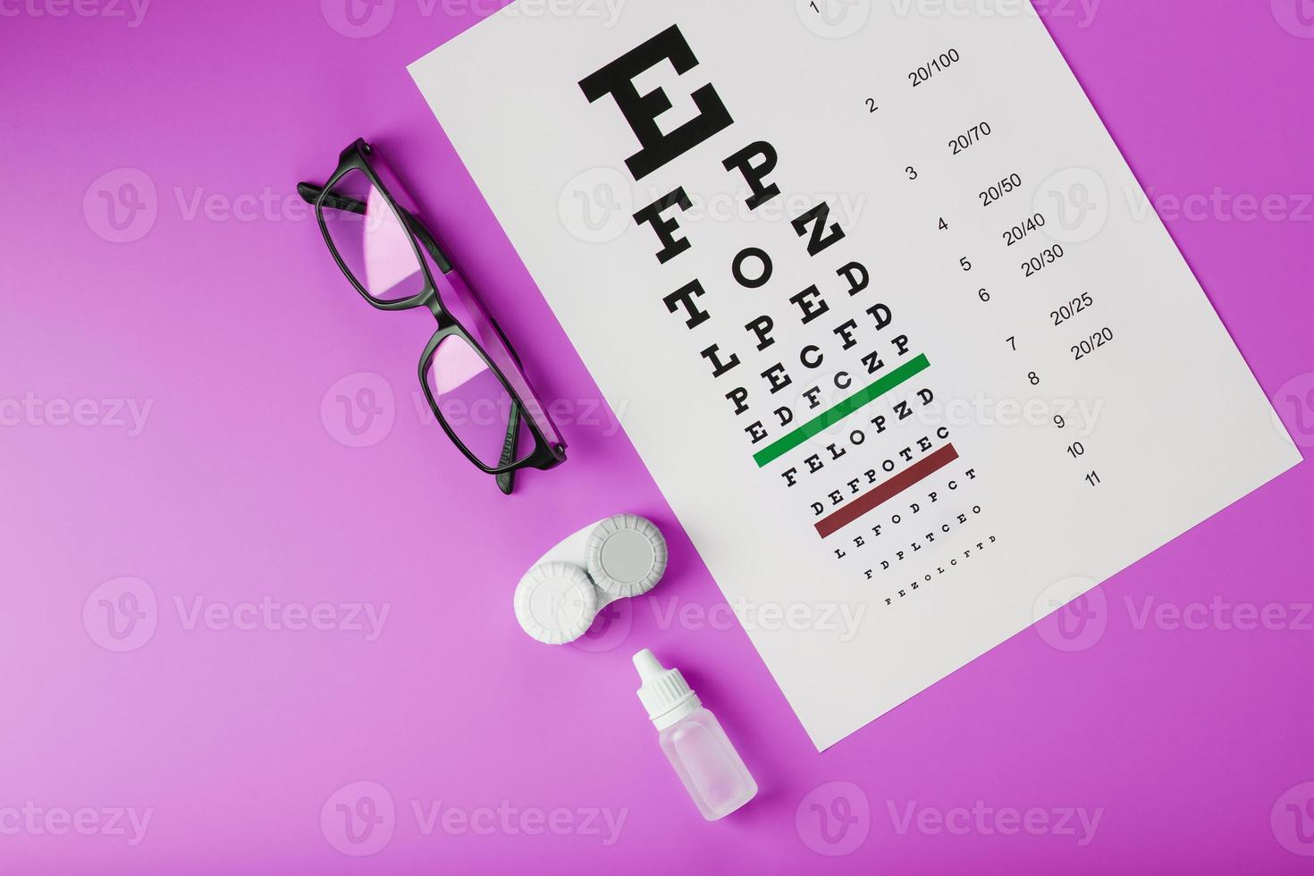 óculos e lentes de acessórios oftálmicos com mesa de teste de visão para correção de visão em um fundo rosa. foto