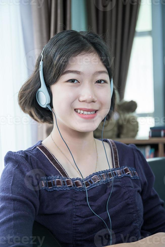 jovem mulher asiática cabelo curto ouvindo música na sala de estar foto