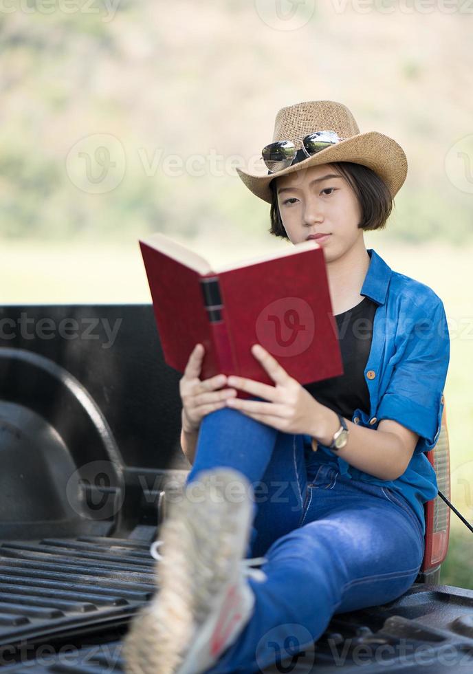 mulher usa chapéu e lê o livro na caminhonete foto