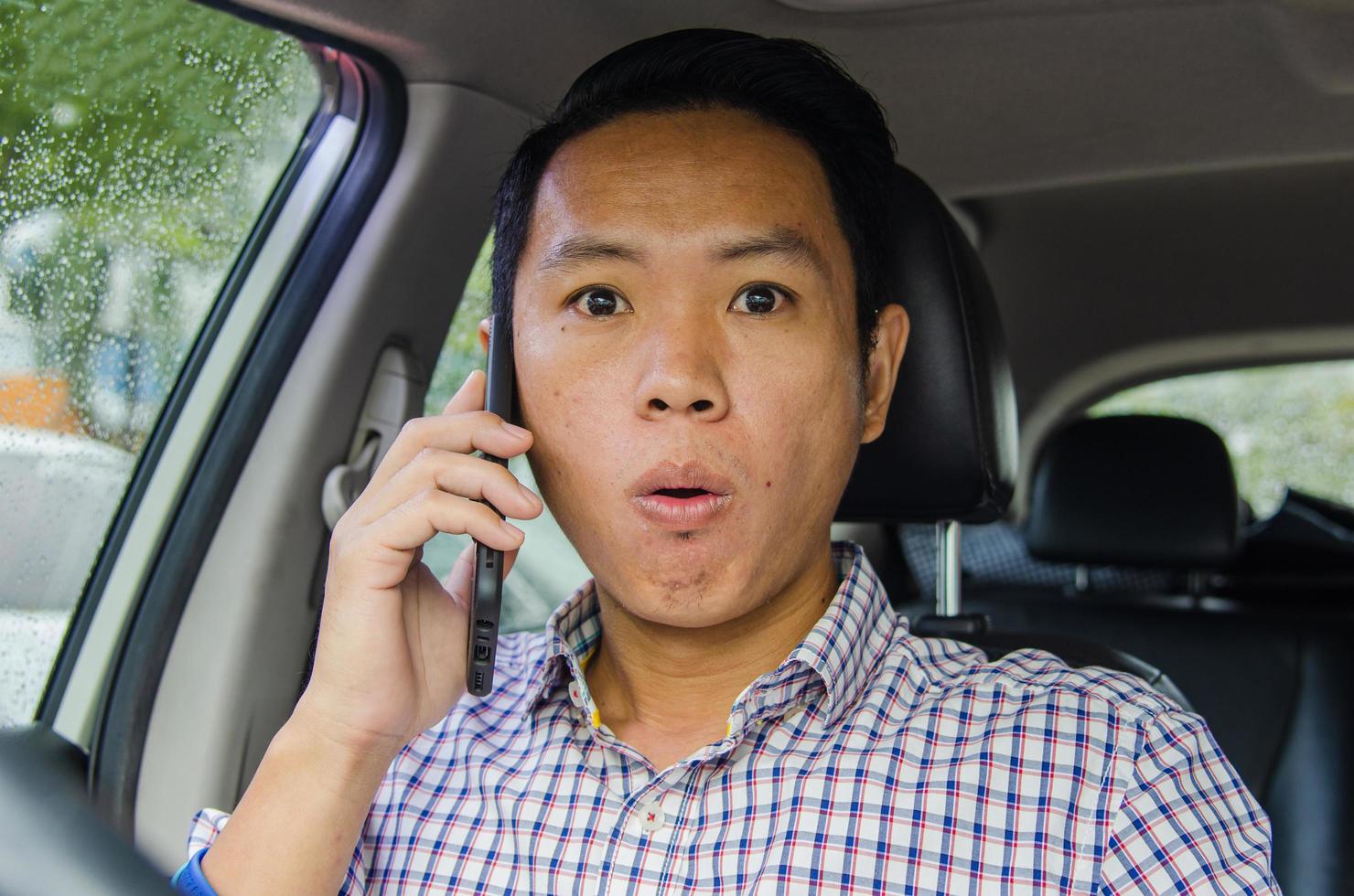 homem chocado falando ao telefone no carro foto