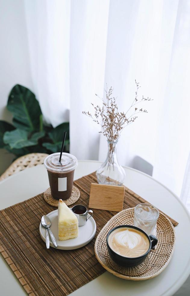 mesa de café, bebida de café gelada e quente com bolo saboroso na mesa em estilo de café aconchegante, estilo minimalista e hipster foto