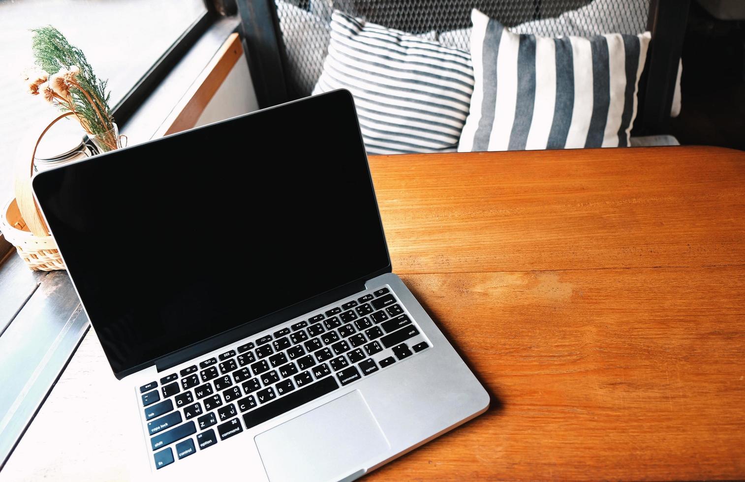 trabalhar em casa, laptop de computador em mesa de madeira em sala aconchegante, trabalhando remotamente durante a auto-quarentena foto