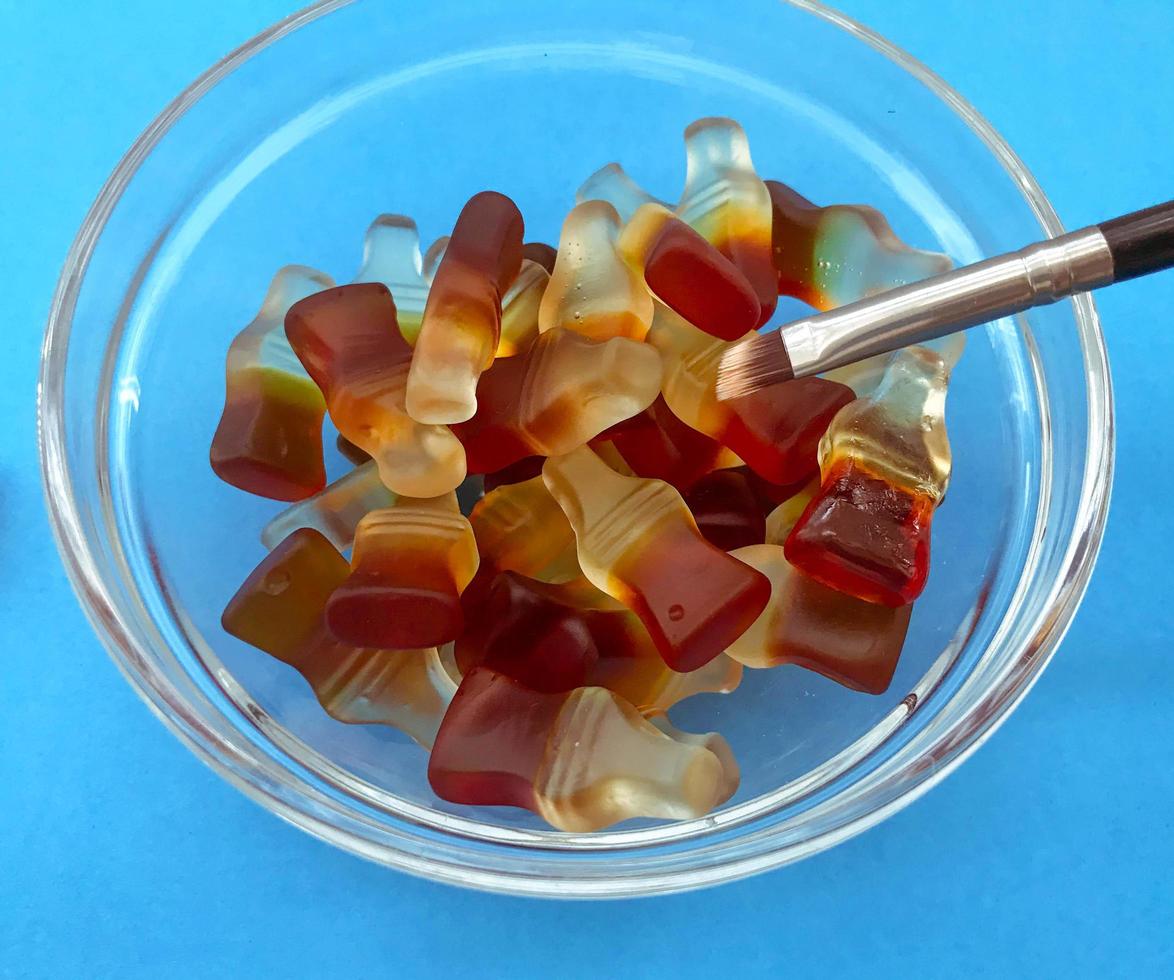 pincel de maquiagem fino. dentro de uma marmelada de vidro transparente em forma de garrafas com limonada. deliciosa sobremesa doce. doces gelatinosos foto