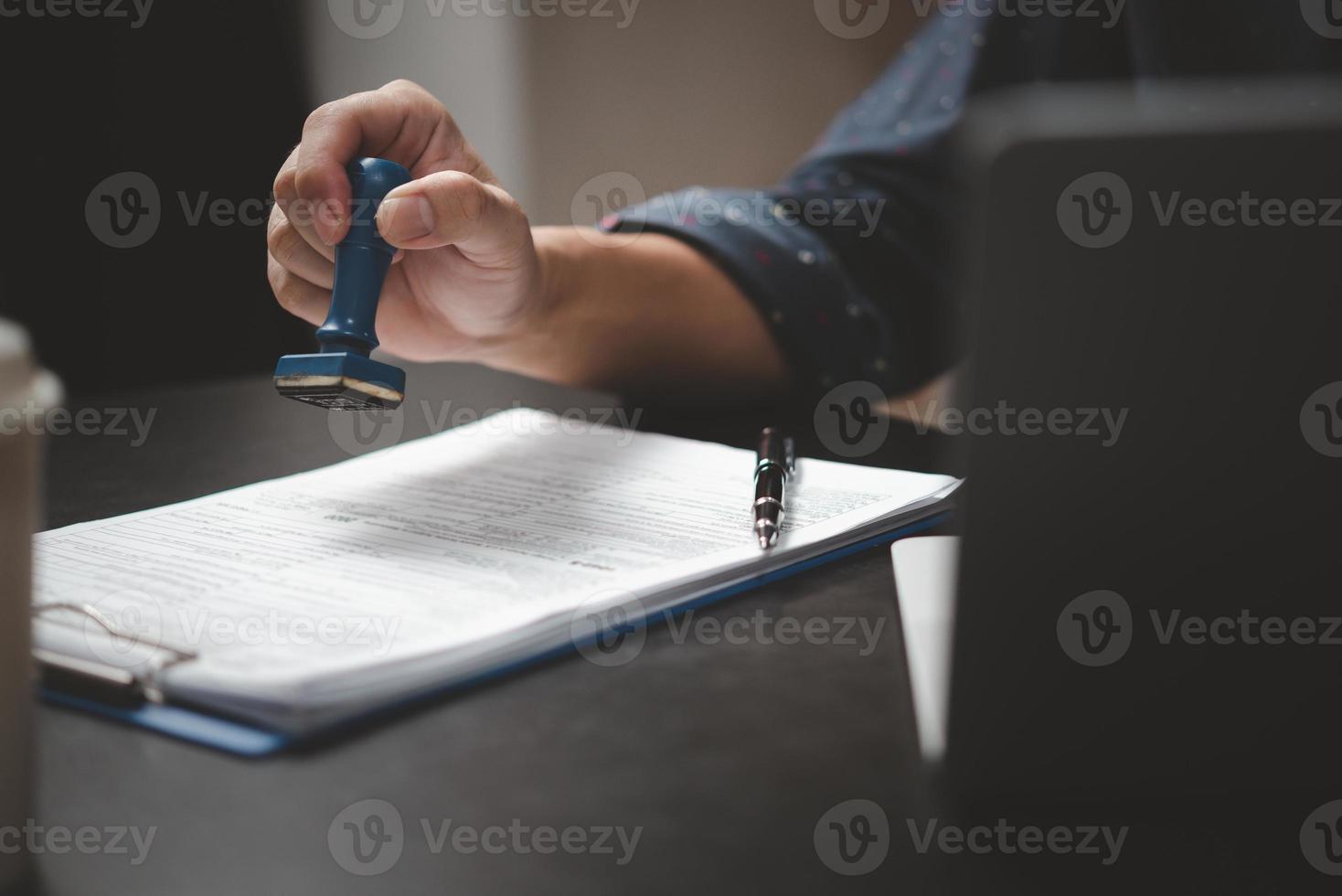 homem carimbando a aprovação de documentos bancários de finanças de trabalho ou de marketing de investimento na mesa. foto