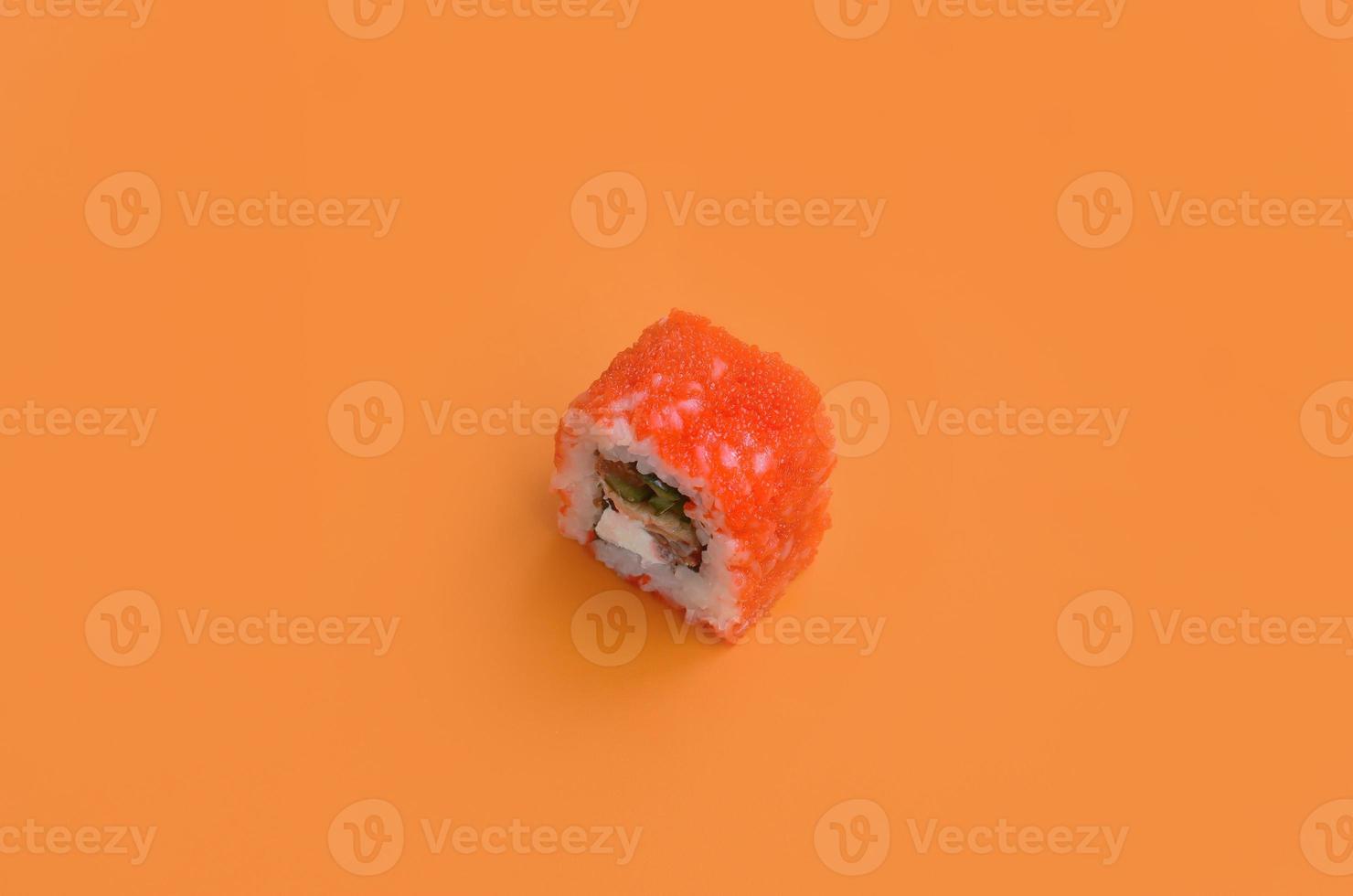 rolo de sushi maki califórnia com caviar em fundo laranja. minimalismo vista superior plana lay com comida japonesa foto