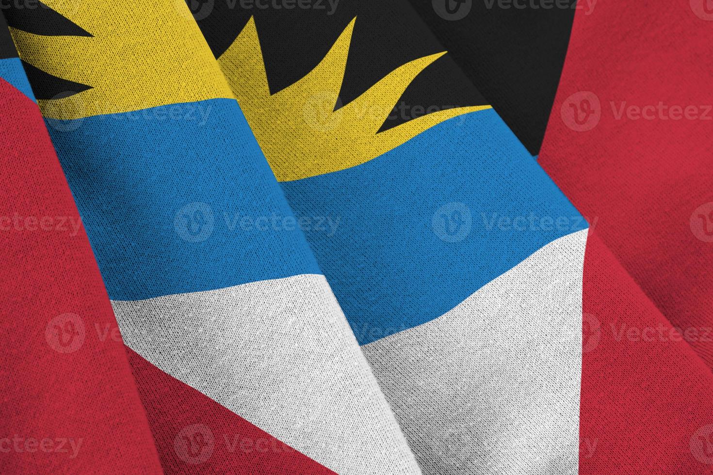 bandeira de antígua e barbuda com grandes dobras acenando de perto sob a luz do estúdio dentro de casa. os símbolos oficiais e cores no banner foto