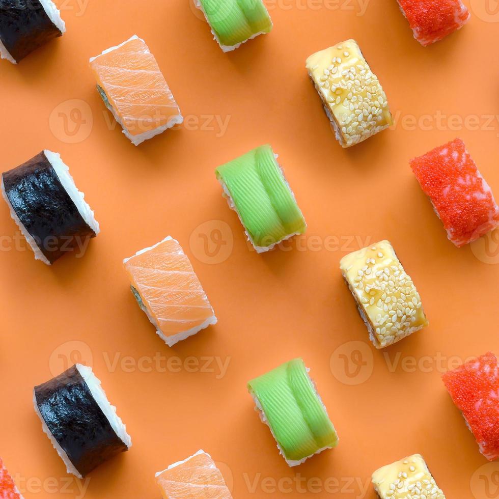 diferentes tipos de rolos de sushi asiáticos em fundo laranja. minimalismo vista superior plana padrão leigo com comida japonesa foto