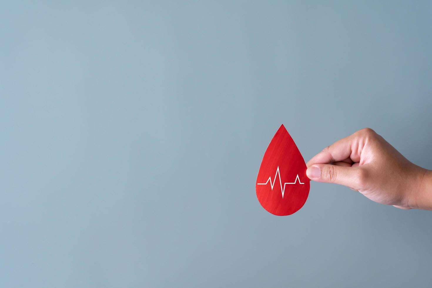 conceito de doação de sangue. humano segurando sinal de sangue com batimento cardíaco. foto