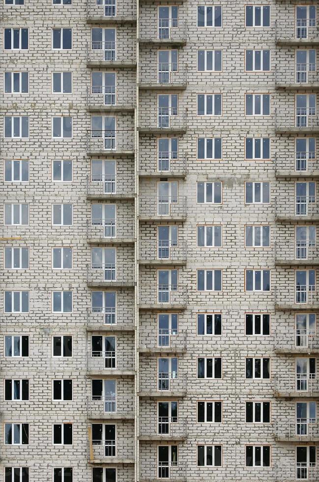 padrão texturizado de uma parede de construção residencial de pedra branca russa com muitas janelas e varanda em construção foto